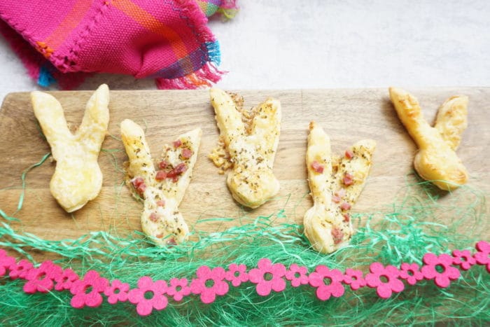 Hasenohren mit Speck und Käse aus Blätterteig - selbstegmachte Blätterteighasen auf Brett mit bunter Deko