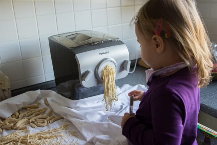 Mädchen steht auf learning tower und hilft beim Nudeln selber machen mit dem Philips Pastamaker - selbstgemachte Spaghetti in wenigen Minuten