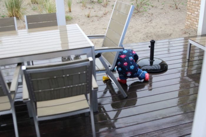 Kind spielt im Regen auf der Tereasse vom Ferienhaus