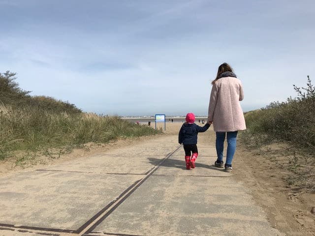 Mama und Kind von hinten, Hand in Hand Spaziergang zum Meer