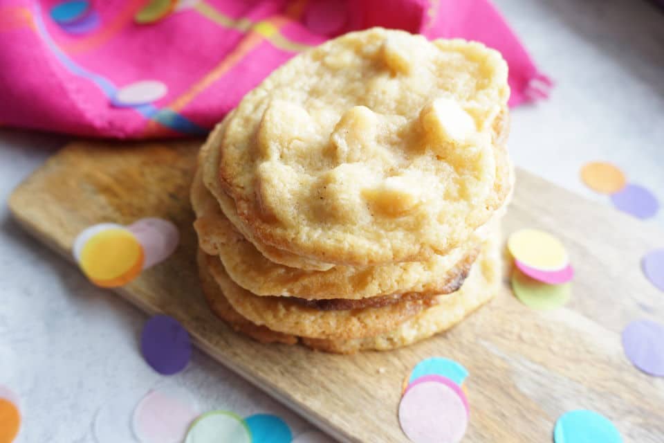 White Chocolate Macadamia Cookies auf einem Holzbrett mit Tuch in pink und buntem Konfetti