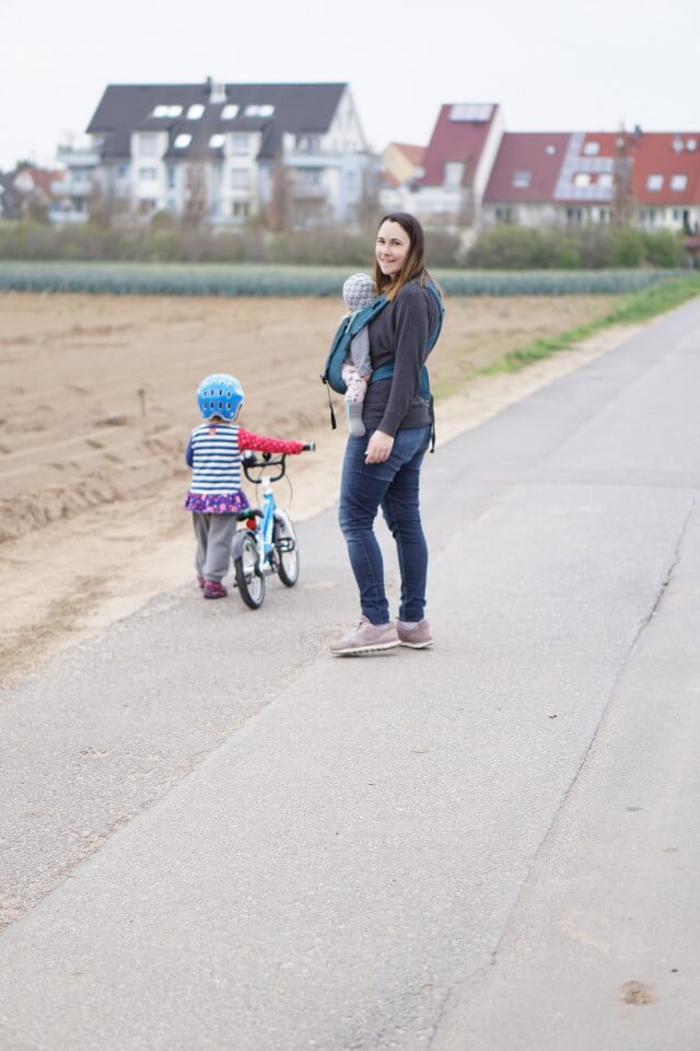 Mama und Töchter - Mama mit Baby in der Trage und Kleinkind mit dem Kinderfahrrad